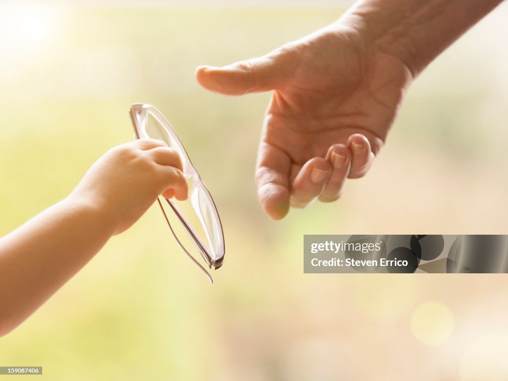 Child handing glasses to a elderly person