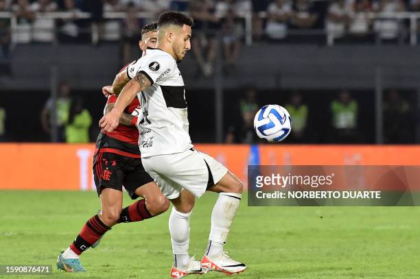 Olimpia's forward Fernando Cardozo fights for the ball with Flamengo's Uruguayan midfielder Giorgian de Arrascaeta during the Copa Libertadores round...