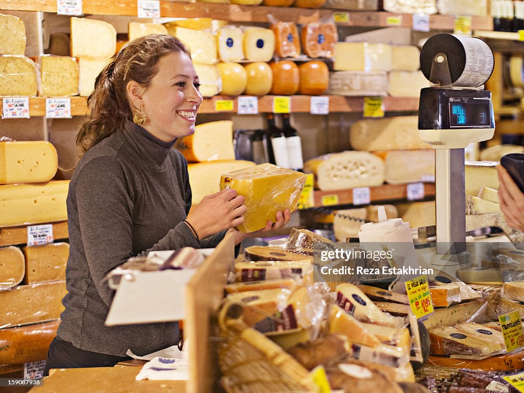 Shop assistant in cheese shop smiles at customer
