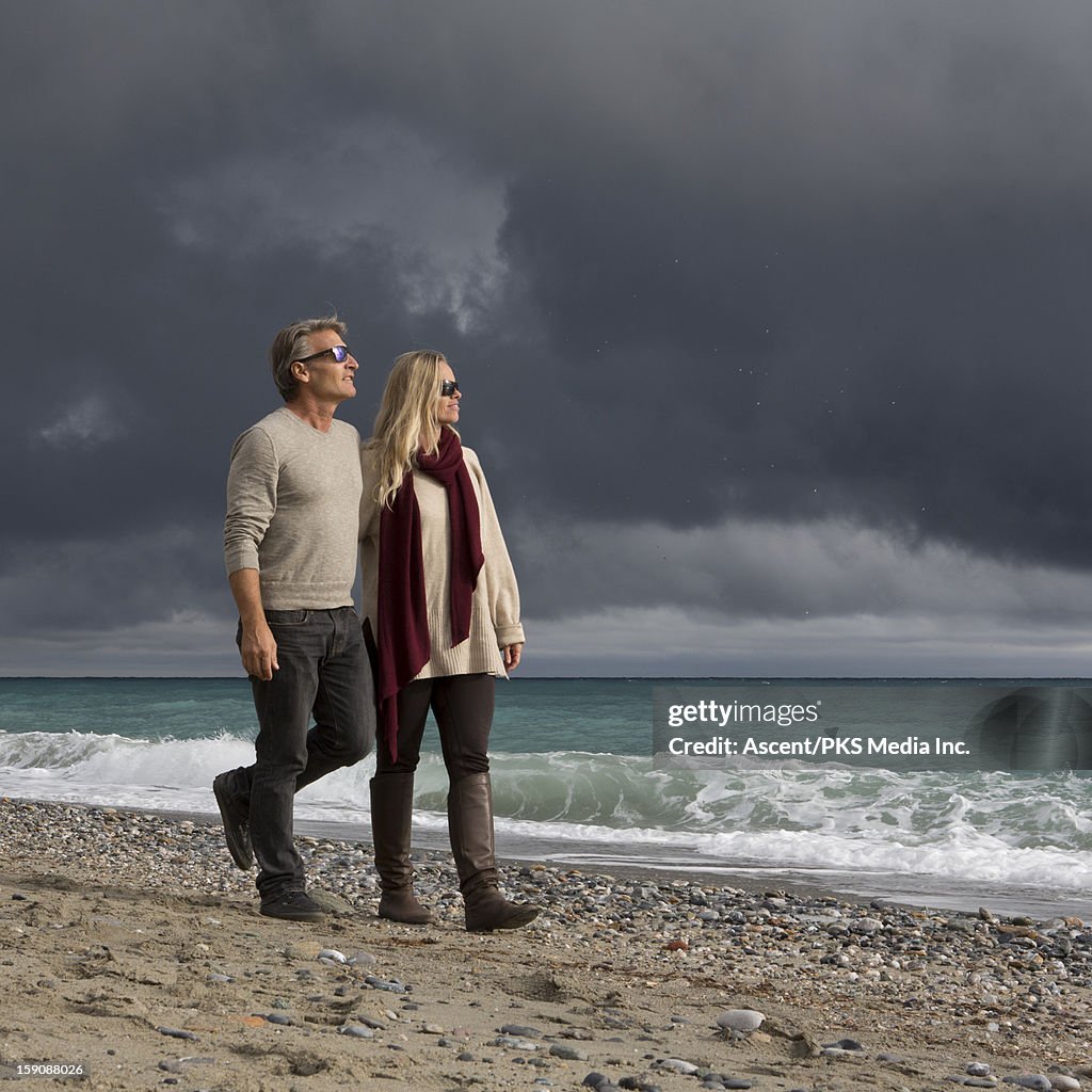 Couple walk along beach after storm clouds pass