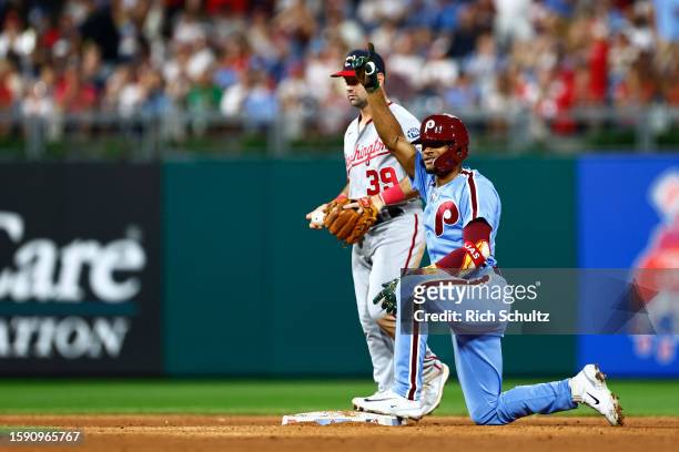Johan Rojas of the Philadelphia Phillies gestures after sliding into second base safely for a double as second baseman Jake Alu of the Washington...