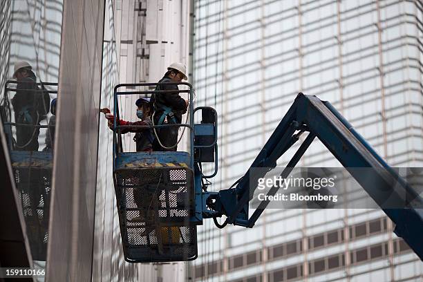 Workers clean the windows of CCB Tower, which houses the local operations of China Construction Bank Corp., in the central business district of Hong...