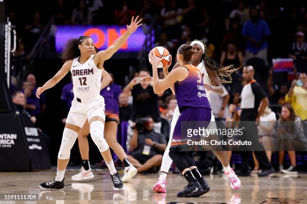 Guard Diana Taurasi of the Phoenix Mercury attempts a shot over forward Nia Coffey of the Atlanta Dream and guard Rhyne Howard to score her 10,000th...