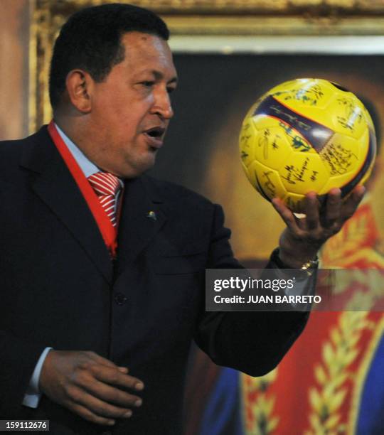 The President of Venezuela Hugo Chavez speaks holding a ball signed and given by the U20 national football team members during a medal ceremony to...