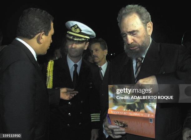 President of Cuba Fidel Castro signs a book about Argentine revolutionary leader Che Guevara for an unidentified Venezuelan military officer as...