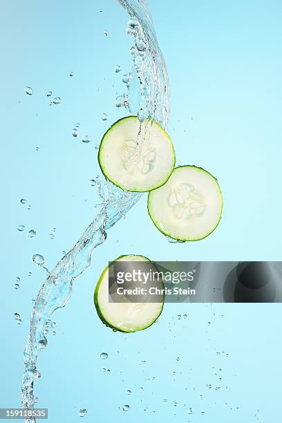 big splash of water and cucumber slices - gurke stock-fotos und bilder