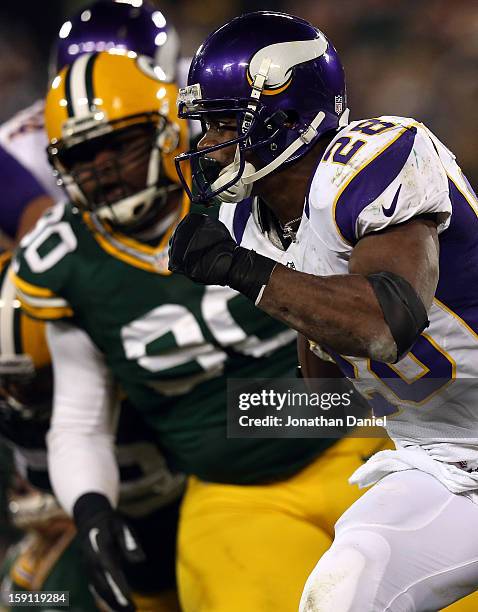 Running back Adrian Peterson of the Minnesota Vikings runs the ball against nose tackle B.J. Raji of the Green Bay Packers during the NFC Wild Card...