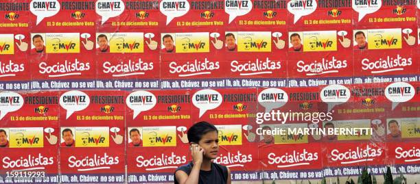 Boy talks on a mobile phone next to electoral posters of Venezuelan President and reelection candidate Hugo Chavez, in Caracas 02 December 2006, in...