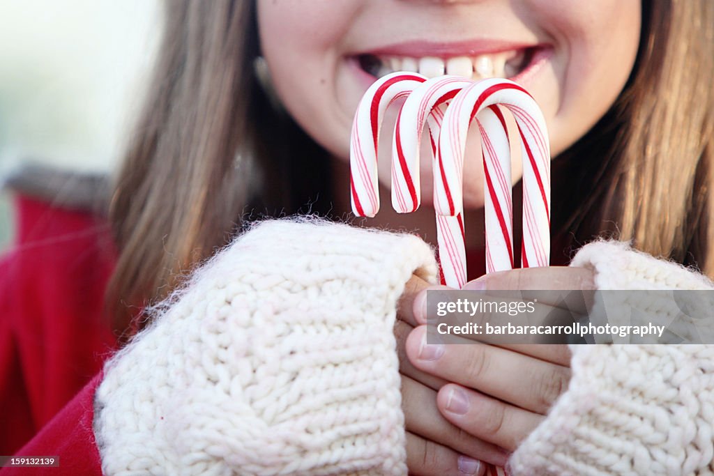 Happy girl holding 3 candy canes