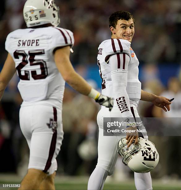 Johnny Manziel of the Texas A&M Aggies smiles as he walks off the field during a timeout against the Oklahoma Sooners during the AT&T Cotton Bowl on...