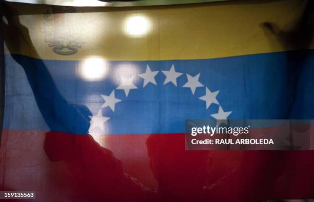 Supporter of Venezuelan President Hugo Chavez holds a Venezuelan flag during a session of the National Assembly in Caracas on January 8, 2013. The...