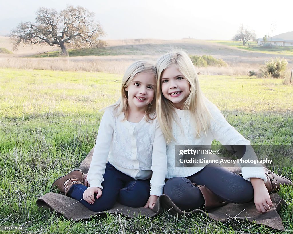 Sisters sitting on blanket field oak tree