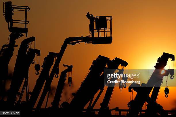 Cranes and boom lifts stand at an equipment rental company near a construction site in Tokyo, Japan, on Tuesday, Jan. 8, 2013. Prime Minister Shinzo...