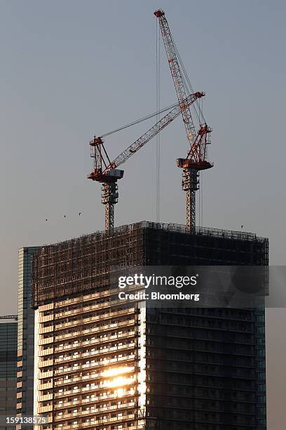 Cranes operate on a construction site in Tokyo, Japan, on Tuesday, Jan. 8, 2013. Prime Minister Shinzo Abe aims to compile Japan's economic stimulus...