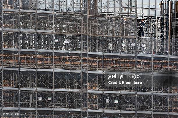 Workers stand on scaffolding on a construction site for a hospital in Tokyo, Japan, on Tuesday, Jan. 8, 2013. Prime Minister Shinzo Abe aims to...
