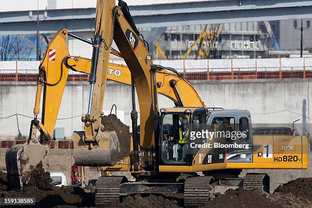 Caterpillar Inc. Excavator, front, and a Kato Works Co. Excavator operate on a construction site in Tokyo, Japan, on Tuesday, Jan. 8, 2013. Prime...
