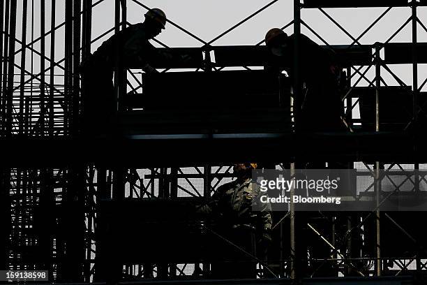 Workers labor on a construction site for a hospital in Tokyo, Japan, on Tuesday, Jan. 8, 2013. Prime Minister Shinzo Abe aims to compile Japan's...