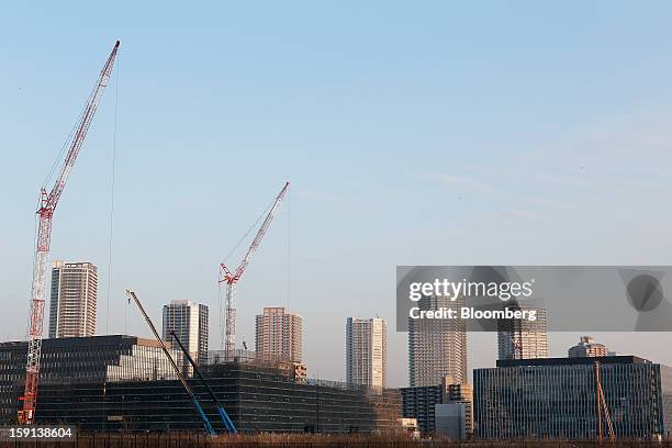 Cranes operate on a construction site for a hospital, left, in Tokyo, Japan, on Tuesday, Jan. 8, 2013. Prime Minister Shinzo Abe aims to compile...