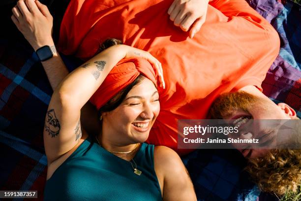 two friends lying on a picnic blanket and laughing - friends picnic stock pictures, royalty-free photos & images