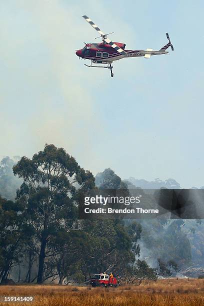 Rural Fire Service members attack the fire at Sandhills from the ground while water-bombing operations take place from the air on January 9, 2013 in...