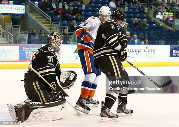 Dany Sabourin of the Hershey Bears watches as teammate Patrick McNeill absorbs a shot on goal and David Ullstrom of the Bridgeport Sound Tigers waits...
