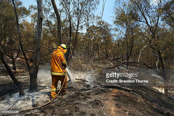 Rural Fire Service member 'mops-up' spot fires at Sandhills on January 9, 2013 in Bungendore, Australia. Temperatures cooled overnight offering...