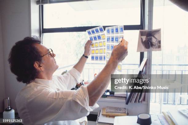 Photographer Bert Stern checks sheets of 35mm photographic transparencies, New York City, United States, 1984.