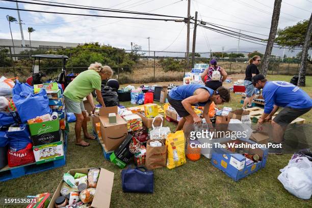Volunteers stack canned goods at War Memorial Stadium in Kahului, Hawaii on August 10, 2023.
