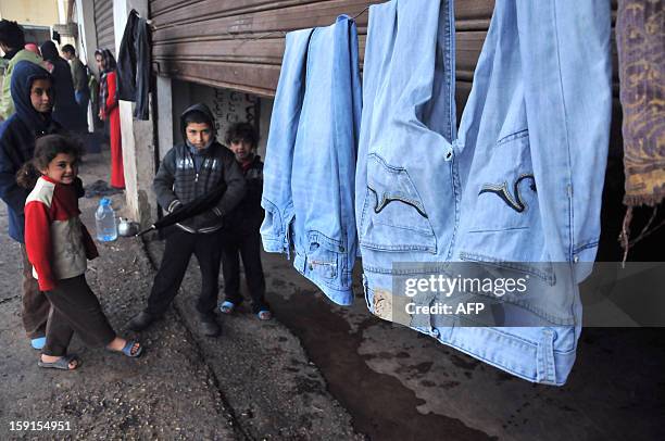 Laundry hangs outside a partially shuttered room as Syrian refugee children stand outside in Kfarkahel village, in the Koura district close to the...