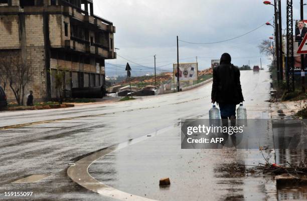 Syrian refugee walks away after filling containers with clean water in the village of Kfarkahel, in the Koura district close to the northern city of...