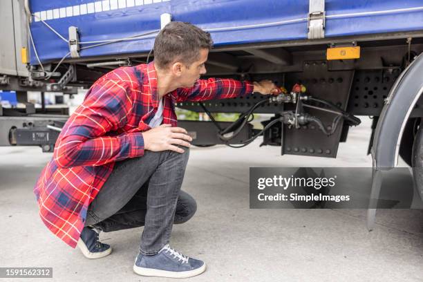truck driver operates valves of the pneumatic suspension of the truck and trailer. - chassis stock pictures, royalty-free photos & images
