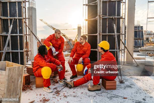 bauarbeiter, die nach der arbeit auf einer baustelle eine pause einlegen - building foundations stock-fotos und bilder