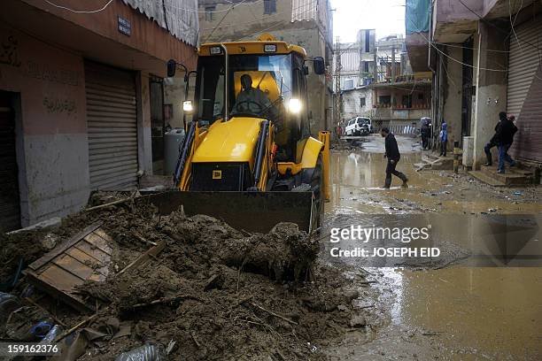 Bulldozer works on removing garbage, mud and water from the flooded streets in Beirut's southern suburb of Hayy al-Sellum on January 9, 2013 as heavy...