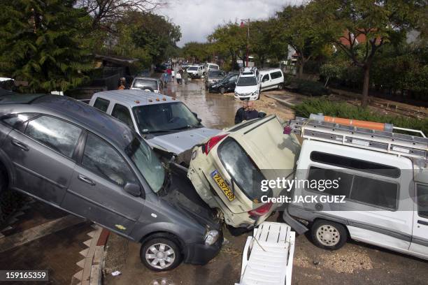 Israeli men look at the damaged cars in Beit Hefer near the Meditrranean coastal city of Netanya, north of Tel Aviv, on January 9 after heavy rains...