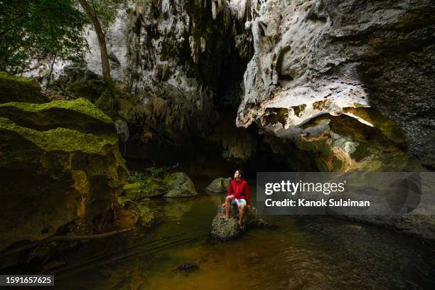 tourist sitting on the rocks watching the nature of the tropical rainforest - speleology stock pictures, royalty-free photos & images