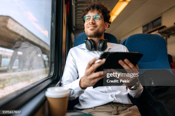 casually clothed handsome man using digital tablet while riding in a train - tåg bildbanksfoton och bilder