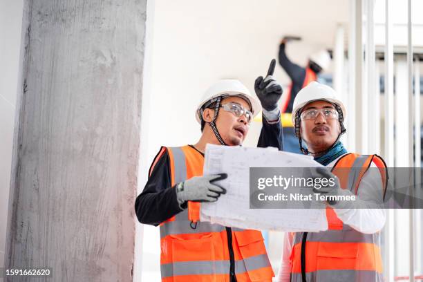 project status reports are essential to project visibility and cost management. team construction engineers discuss a blueprint or project task details to follow up on progress at a construction site. - continuing development stock pictures, royalty-free photos & images