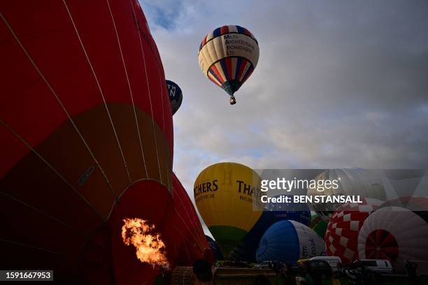 Hot air balloons take to the air in a Mass Ascent at dawn during the Bristol international balloon fiesta, in Ashton Court, in Bristol, in the west...