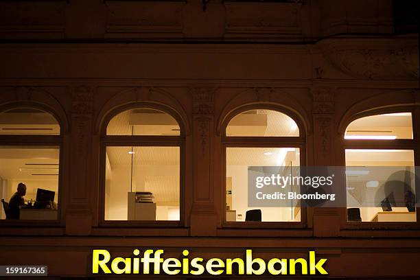 Bank workers are seen at work through the windows of a Raiffeisen Bank International AG branch in Prague, Czech Republic, on Tuesday, Jan. 8, 2013....