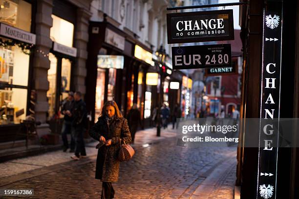 Pedestrians pass a sign advertising euro currency rates outside a money exchange in Prague, Czech Republic, on Tuesday, Jan. 8, 2013. The Czech...