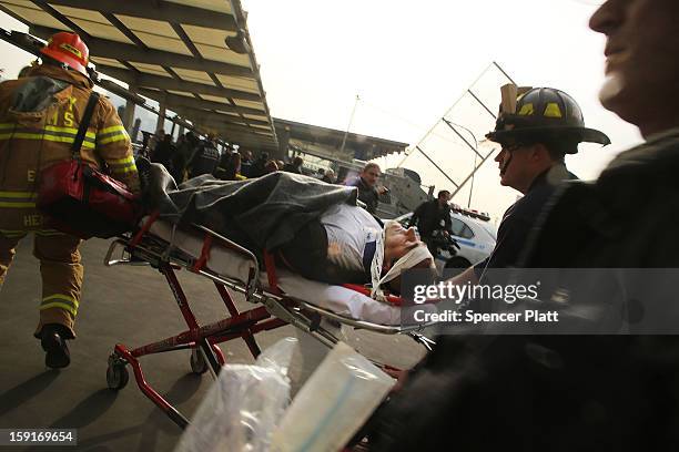 An injured person is carried to a waiting ambulance following an early morning ferry accident during rush hour in Lower Manhattan on January 9, 2013...