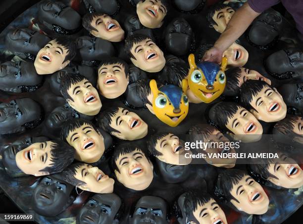 Worker shows masks of Brazilian football star Neymar, the president of the Brazilian Supreme Court Joaquim Barbosa and the mascot of the Brazil 2014...