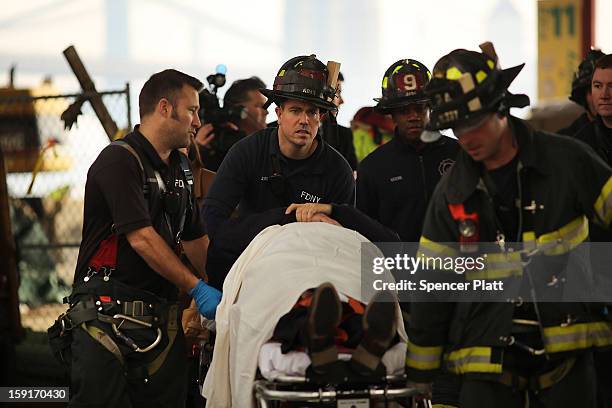 An injured person is carried to a waiting ambulance following an early morning ferry accident during rush hour in Lower Manhattan on January 9, 2013...