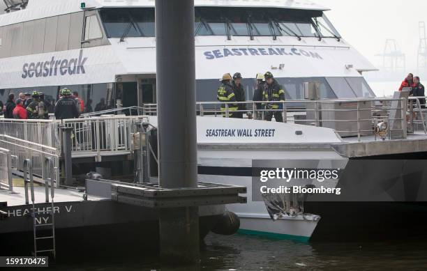 New York Fire Department firefighters stand above damage on a Seastreak Wall Street commuter ferry in New York, U.S., on Wednesday, Jan. 9, 2013. A...