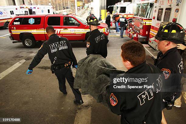 An injured person is carried to a waiting ambulance following an early morning ferry accident during rush hour in Lower Manhattan on January 9, 2013...