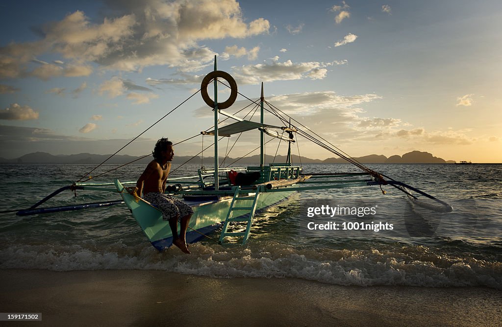 Philippino with his traditional banca outrigger boats in the philippines