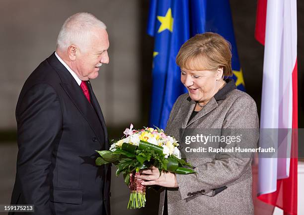 Vaclav Klaus , president of the Czech Republic, hands over flowers to German Chancellor Angela Merkel , when he arrives at the Chancellery on January...