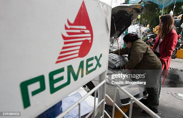 An attendant checks a custmer's engine at a Pemex station in Mexico City, Mexico, on Tuesday, Jan. 8, 2013. Mexico’s government is speeding up the...