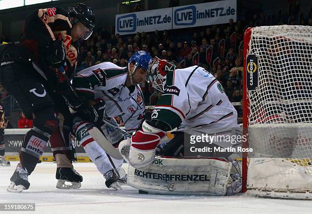 Stephan Wilhelm of Hannover and Justin Forrest of Augsburg battle for the puck in front of the net during the DEL match between Hannover Scorpions...