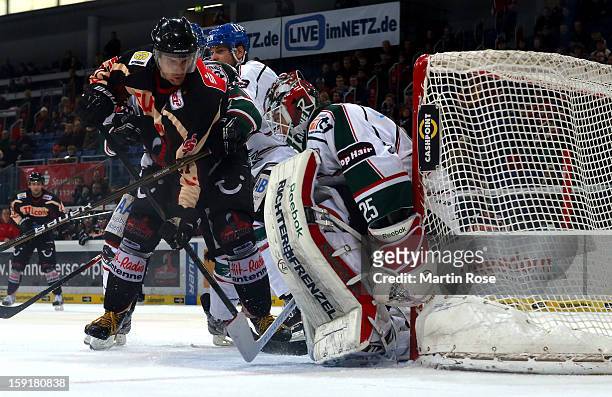 Ivan Ciernik of Hannover and Justin Forrest of Augsburg battle for the puck in front of the net during the DEL match between Hannover Scorpions and...